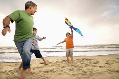 Dad and kids flying a kite on the beach