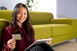 Lady sitting on the floor in front of the couch with her debit card checking her reward plus points